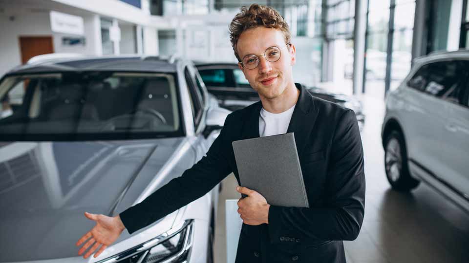 Ein Verkäufer zeigt auf ein Auto und erklärt dem Kunden die Konditionen beim Auto verkaufen Düsseldorf